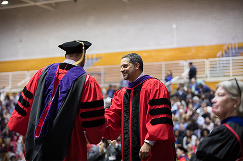 man shaking a students hand at graduation ceremony