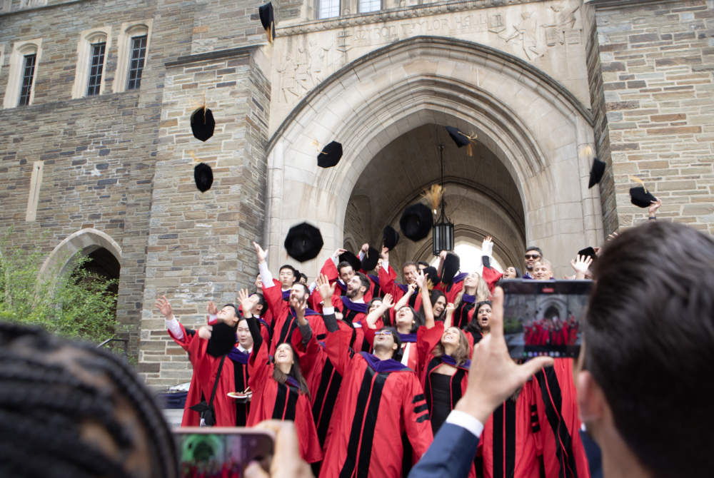 a group of students posing for a picture in their regalia while tossing their hats in the air