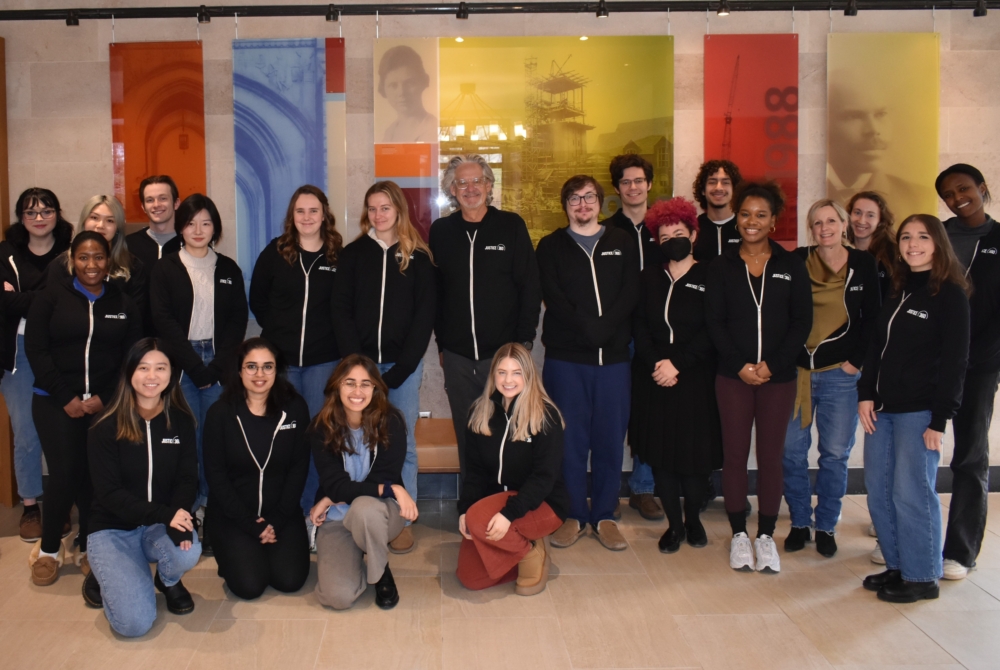 class photo of students and faculty in matching hoodies