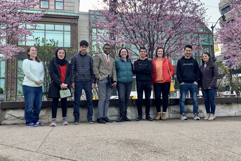 group of students and faculty in front of blossoming trees