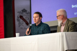 man at a table speaking into a microphone