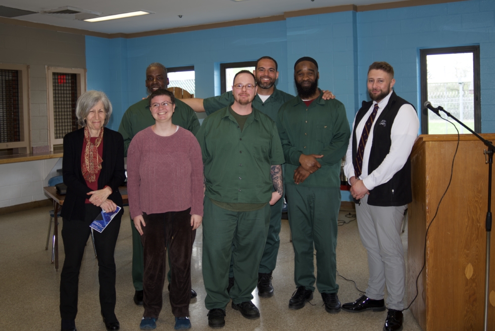 group of men in green prison wear with instructors