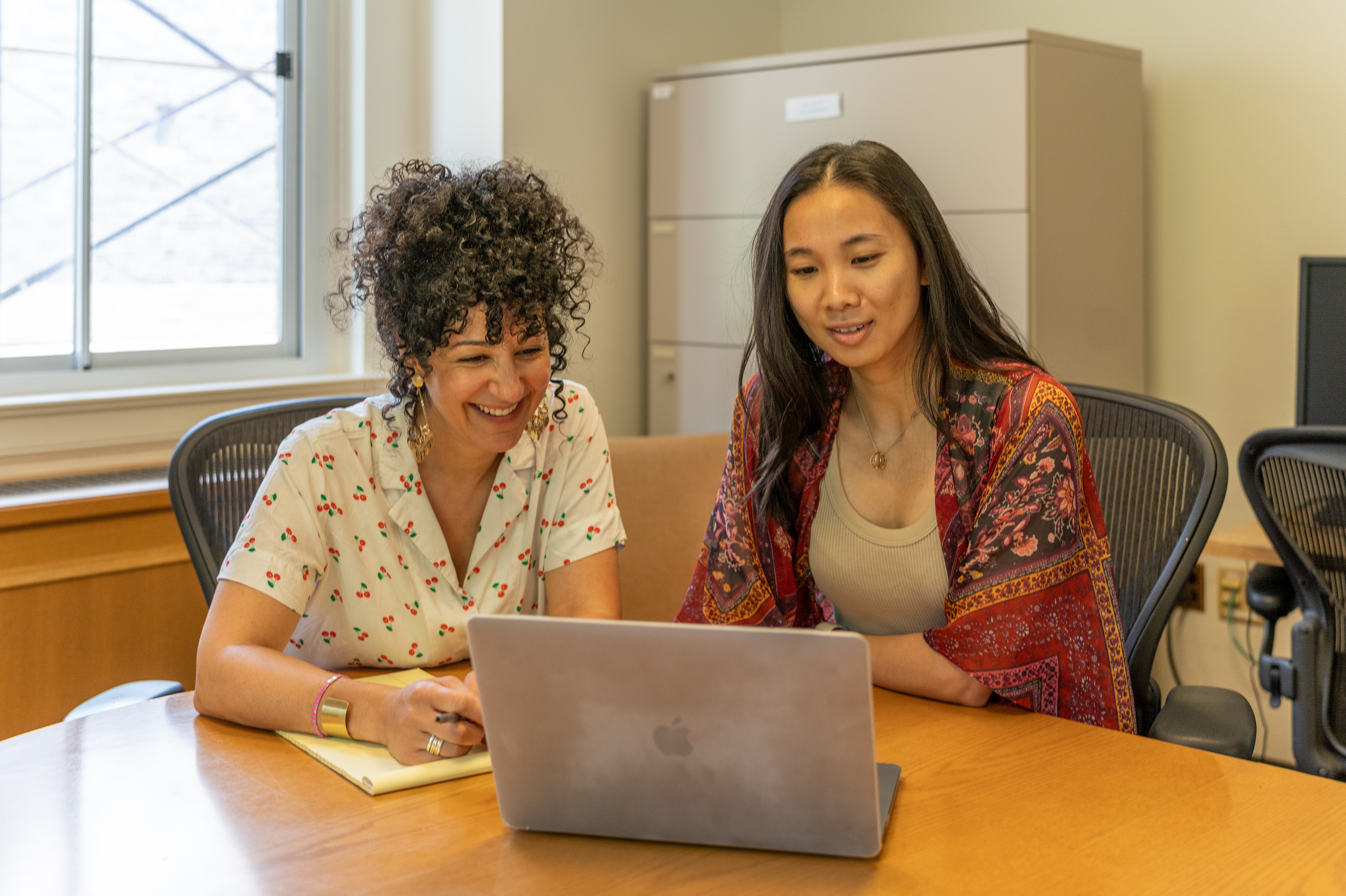 a student and teacher looking a laptop and smiling