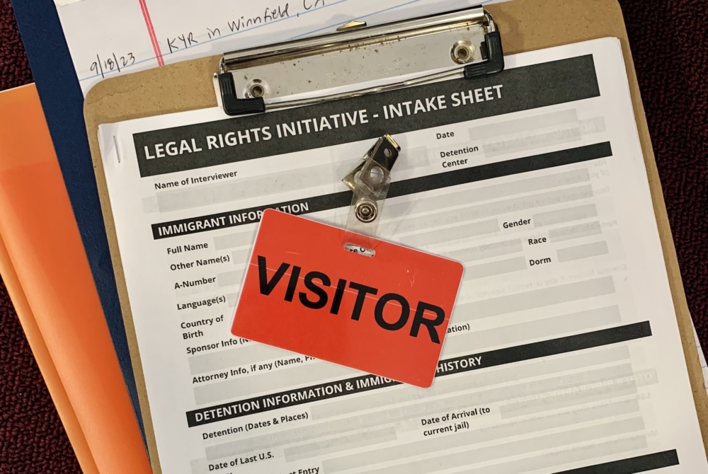 clipboard with papers and orange tag that says Visitor