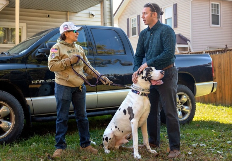 Army veteran Ana Chan and Jimmy Hardwick talking next to truck with dog.